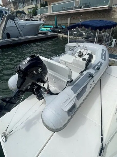 Slide: The Image of A small inflatable boat with an outboard motor is docked. It features a simple steering console. - 49