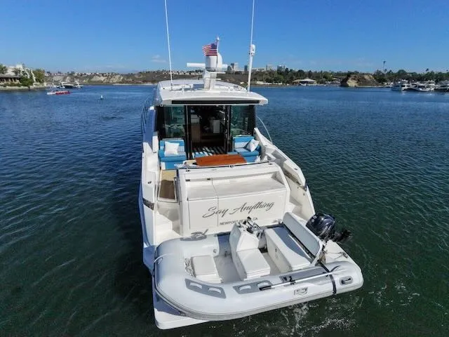 Slide: The Image of 2017 Tiara Yachts C53 Coupe on calm water, featuring a dinghy and American flag. - 6
