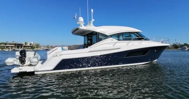 Slide: The Image of The 2017 Tiara Yachts C53 Coupe glides elegantly on calm water. It features a sleek design with a white and blue hull. - 2