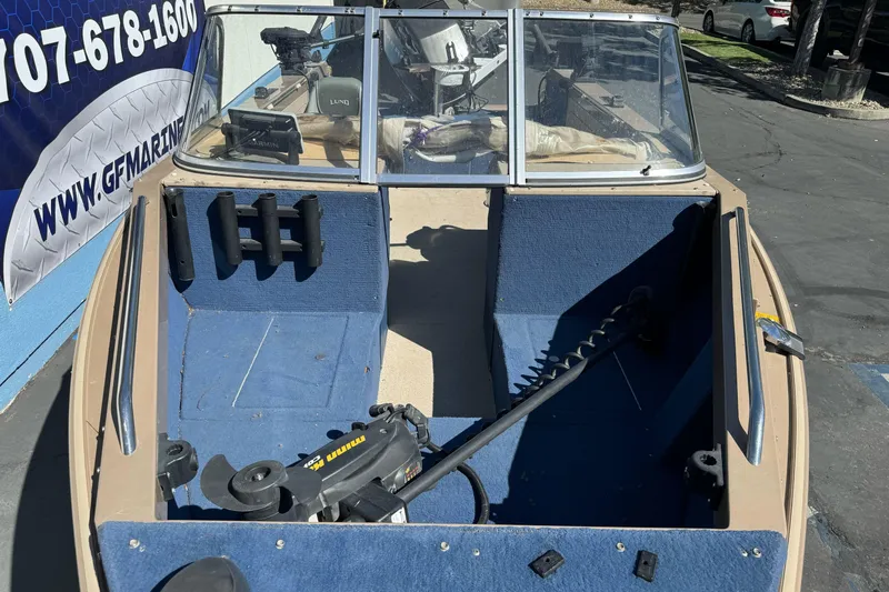 Slide: The Image of 1998 Lund 1700 Pro Sport boat interior with blue carpet and fishing equipment. - 11