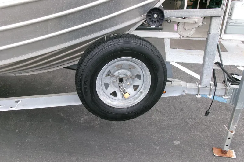 Slide: The Image of 2017 Klamath Bayrunner 19 Baja boat trailer with spare tire on asphalt. - 16