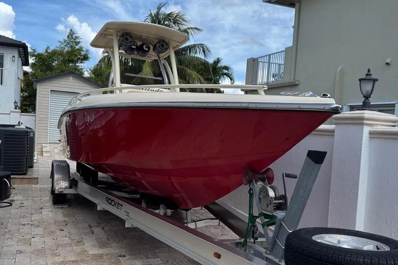 The Image of Red 2014 Latitude 28 CC boat on trailer, parked in driveway with palm trees. - 1