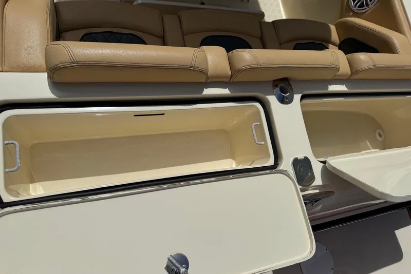Slide: The Image of 2014 Latitude 28 CC boat interior with open storage compartments and tan seating. - 21