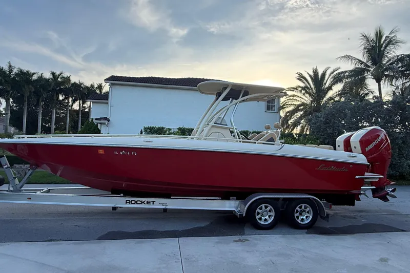 Slide: The Image of Red 2014 Latitude 46 28 CC boat on trailer, parked near palm trees at sunset. - 22