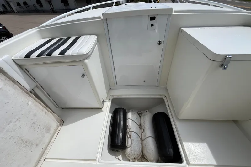 Slide: The Image of 1994 Intrepid 30 Open Cuddy boat interior with storage compartments and striped seat cushion. - 13