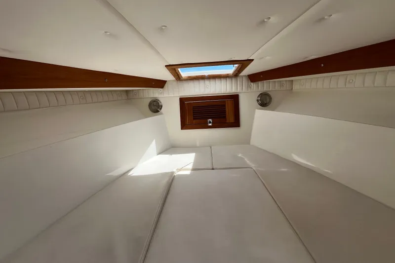 Slide: The Image of Interior of a 1994 Intrepid 30 Open Cuddy, featuring white cushions and wooden accents. - 23
