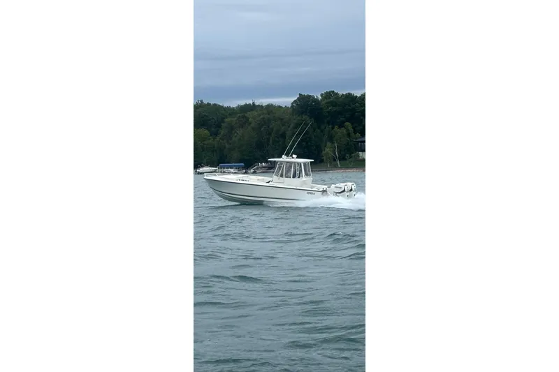 Slide: The Image of 1994 Intrepid 30 Open Cuddy boat cruising on a lake with forested shoreline. - 3