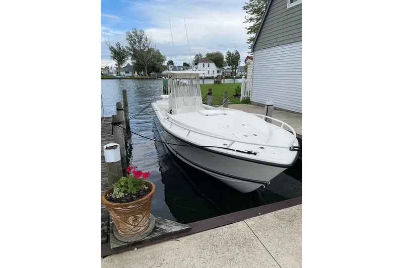 Slide: The Image of 1994 Intrepid 30 Open Cuddy boat docked by a lakeside house, with potted flowers nearby. - 4