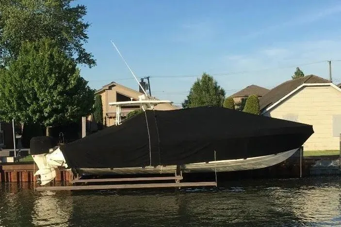 Slide: The Image of Covered 1994 Intrepid 30 Open Cuddy boat docked by waterfront homes. - 5