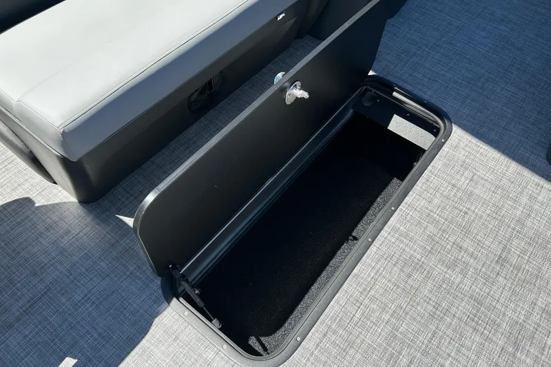 Slide: The Image of Sun Tracker Sportfish 24 XP3 2026 boat storage compartment with open hatch on gray flooring. - 35