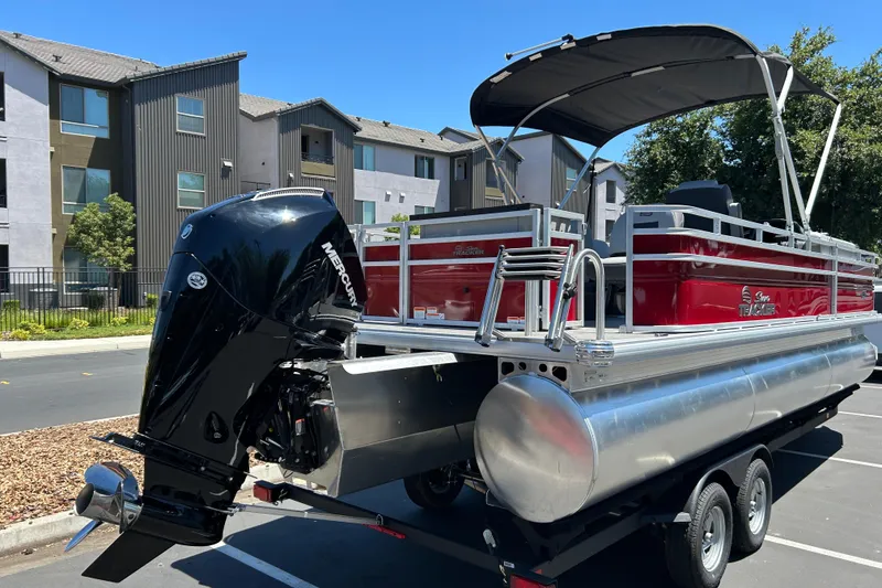 Slide: The Image of 2026 Sun Tracker Sportfish 24 XP3 pontoon boat with Mercury outboard motor in a parking lot. - 5