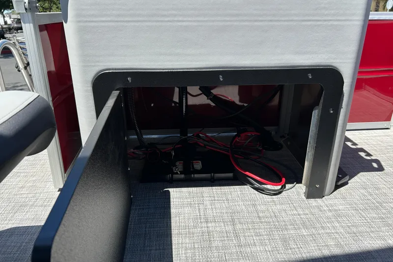 Slide: The Image of 2026 Sun Tracker Sportfish 24 XP3 boat storage compartment with visible wiring and red exterior. - 26