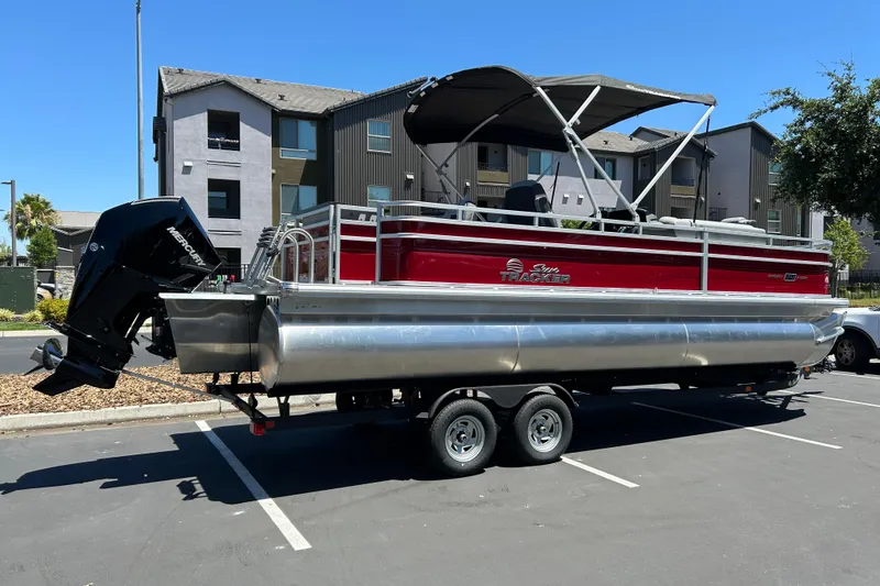 Slide: The Image of 2026 Sun Tracker Sportfish 24 XP3 pontoon boat on trailer in parking lot. - 2