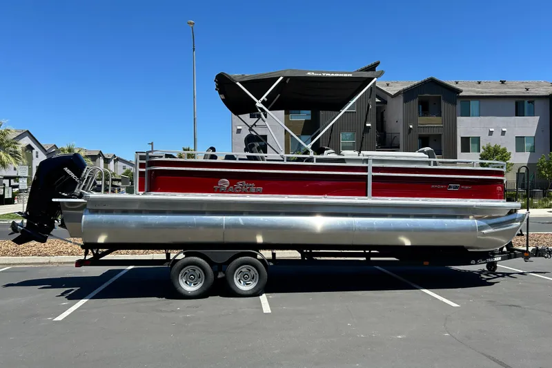 The Image of 2026 Sun Tracker Sportfish 24 XP3 pontoon boat on trailer in parking lot. - 0
