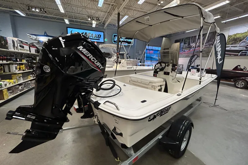 Slide: The Image of 2026 Mako Pro Skiff 17 CC boat with Mercury engine displayed indoors. - 1