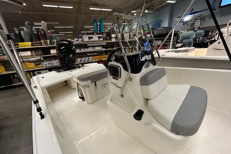 Slide: The Image of 2026 Mako Pro Skiff 17 CC boat displayed in a showroom with seating and console. - 3