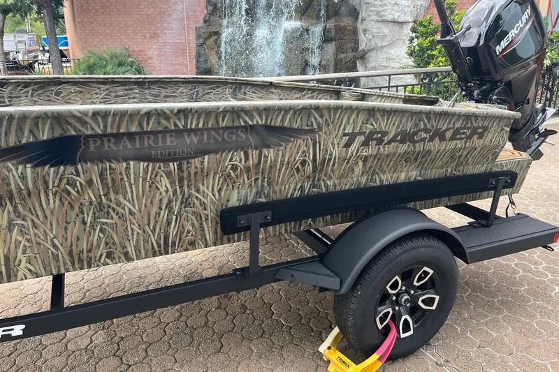 Slide: The Image of 2026 Tracker Grizzly 1650 T Prairie Wings Edition boat with camouflage design on a trailer. - 2