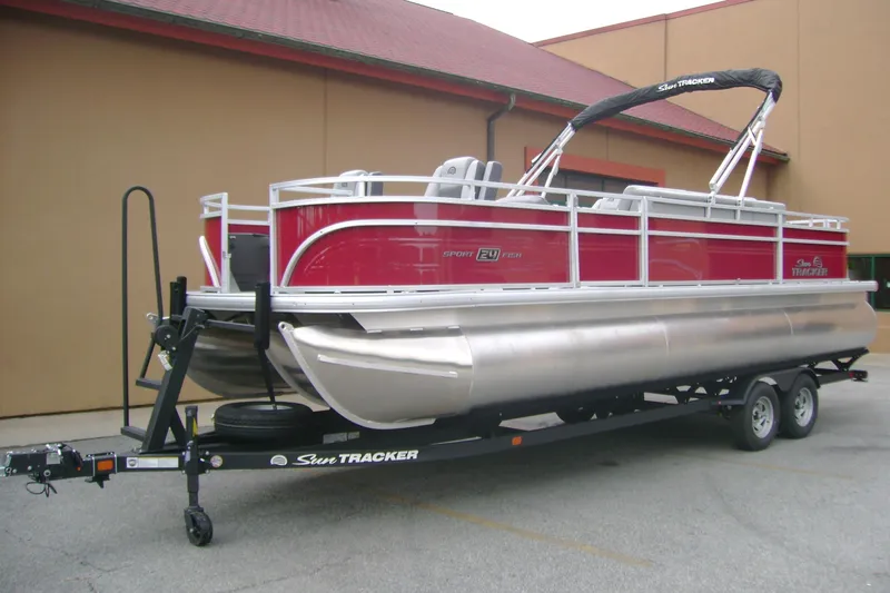 Slide: The Image of 2026 Sun Tracker Sportfish 24 XP3 pontoon boat on trailer, red and silver design. - 3