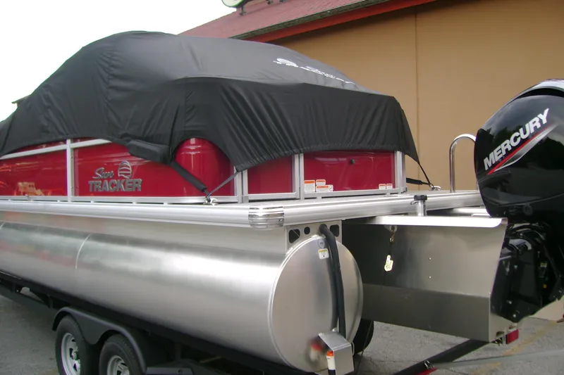 Slide: The Image of 2026 Sun Tracker Sportfish 24 XP3 pontoon boat with Mercury outboard motor, covered and parked. - 6