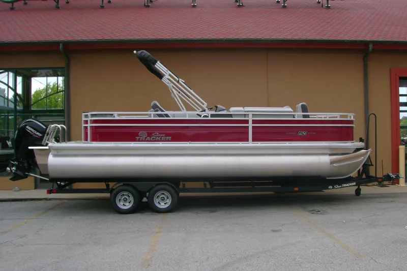 The Image of 2026 Sun Tracker Sportfish 24 XP3 pontoon boat on trailer, parked outdoors. - 0
