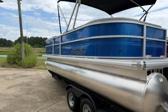 Slide: The Image of 2026 Sun Tracker Party Barge 20 DLX pontoon boat on trailer, blue exterior, parked outdoors. - 8