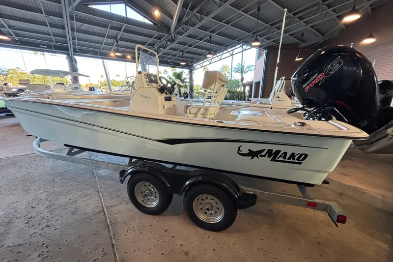 The Image of 2026 Mako Pro Skiff 19 CC boat on trailer in covered showroom. - 0