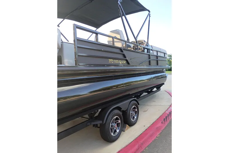 The Image of 2026 Ranger 223FC pontoon boat on trailer, featuring sleek black design and canopy. - 0