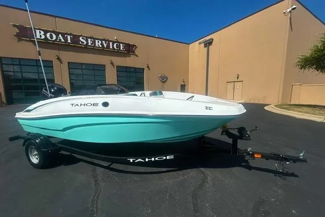Slide: The Image of 2026 Tahoe T16 boat in mint green, parked outside a boat service center. - 2