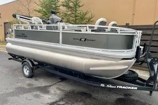 Slide: The Image of 2026 Sun Tracker Bass Buggy 18 DLX pontoon boat on trailer, parked outdoors. - 1