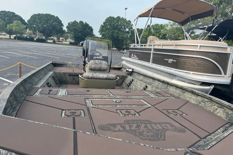 Slide: The Image of 2026 Tracker Grizzly 2072 CC boat in parking lot, featuring spacious deck and camouflage seating. - 8