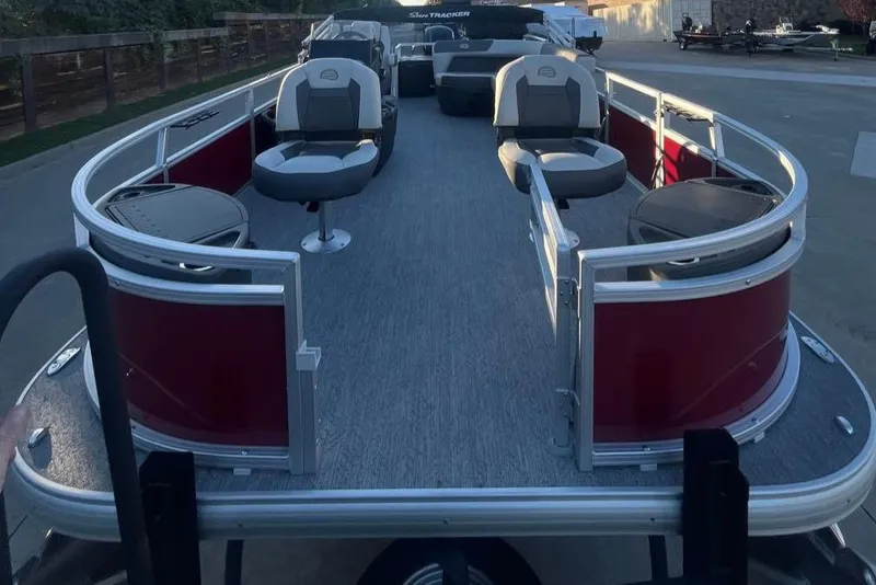 Slide: The Image of 2026 Sun Tracker Bass Buggy 18 DLX pontoon boat with seating and storage, docked outdoors. - 2