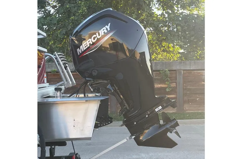 Slide: The Image of 2026 Sun Tracker Bass Buggy 18 DLX with Mercury outboard motor in a driveway. - 3