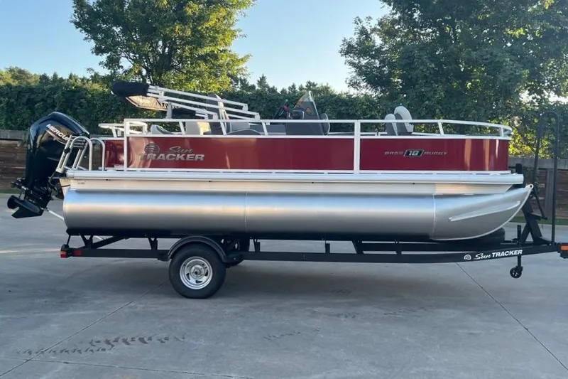The Image of 2026 Sun Tracker Bass Buggy 18 DLX pontoon boat on trailer, parked outdoors. - 0