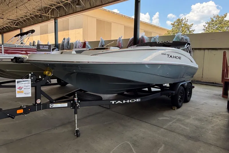 The Image of 2026 Tahoe 1950 boat on trailer in showroom, under covered area. - 0
