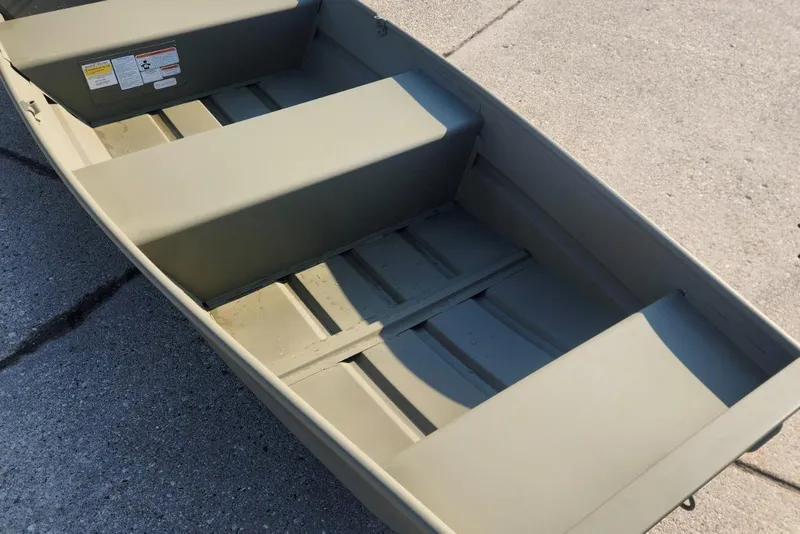 The Image of 2026 Tracker Grizzly 12 Jon boat interior, showcasing seating and storage on concrete surface. - 0