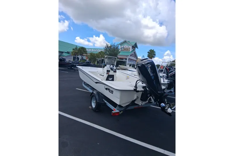 Slide: The Image of 2026 Mako Pro Skiff 17 CC boat on trailer in parking lot, under cloudy sky. - 2