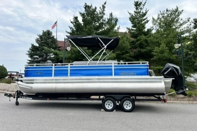 The Image of 2026 Sun Tracker Sportfish 24 XP3 pontoon boat on trailer, parked outdoors. - 0