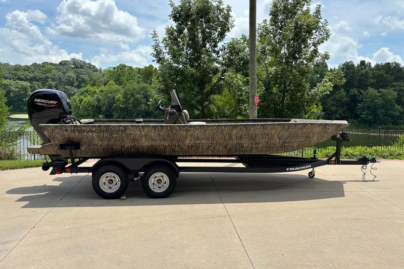 The Image of 2026 Tracker Grizzly 2072 CC boat on trailer, parked outdoors near a lake. - 0