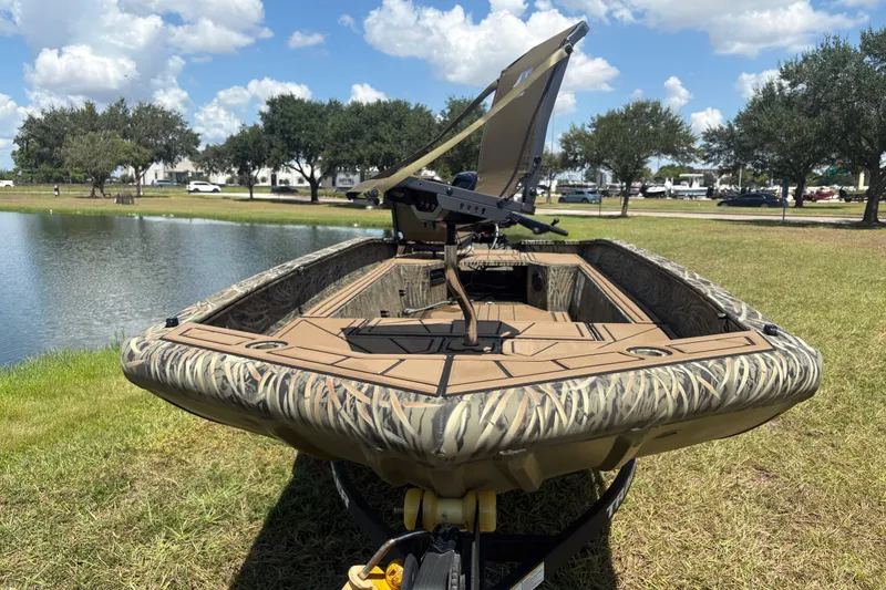 Slide: The Image of 2026 Tracker Grizzly 1650 T Prairie Wings Edition boat by a lake under blue sky. - 31
