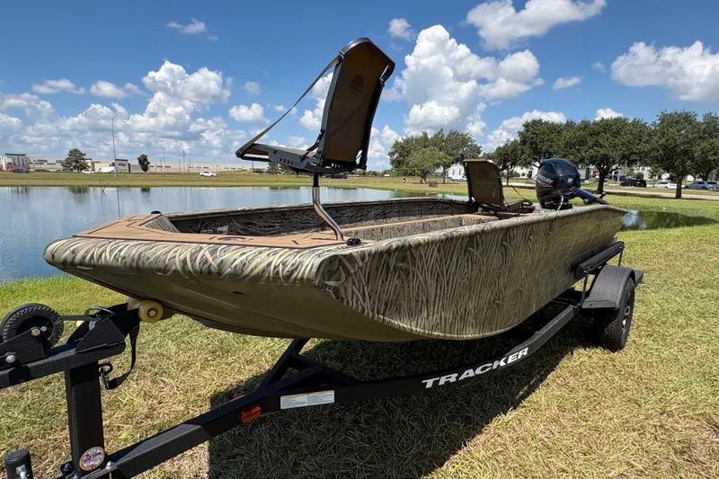 Slide: The Image of 2026 Tracker Grizzly 1650 T Prairie Wings Edition boat on trailer by a lake. - 32