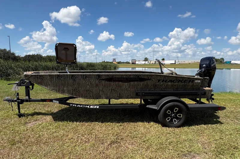 Slide: The Image of 2026 Tracker Grizzly 1650 T Prairie Wings Edition boat on trailer by a lake. - 33