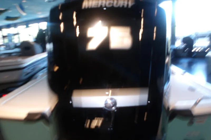 Slide: The Image of Blurry image of a 2026 Mako Pro Skiff 17 CC boat in a showroom. - 9