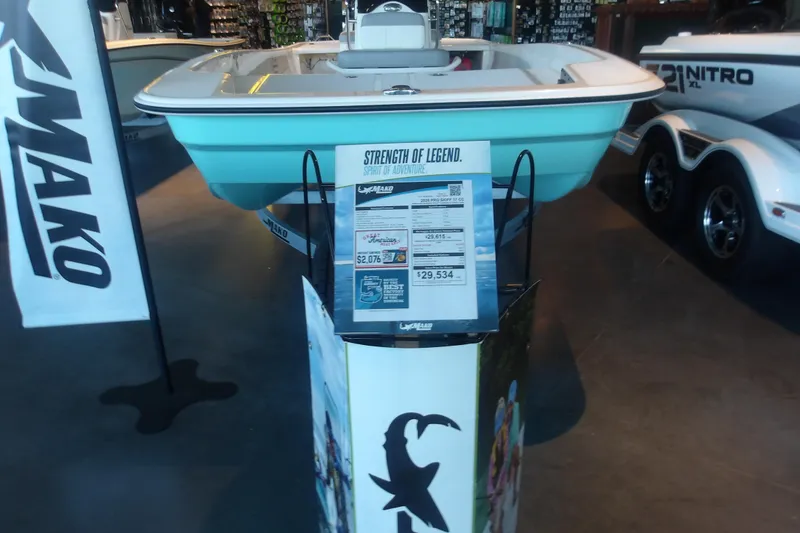 Slide: The Image of 2026 Mako Pro Skiff 17 CC boat displayed in showroom with promotional materials. - 3