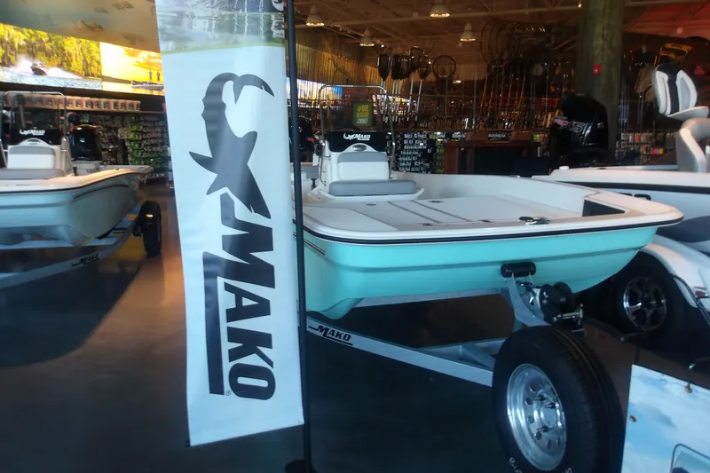 Slide: The Image of 2026 Mako Pro Skiff 17 CC boat displayed in a showroom with Mako banner. - 2