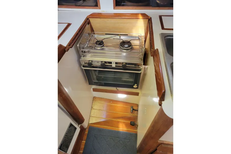 Slide: The Image of 1981 Sea Sprite 34 yacht kitchen with stove and oven, featuring wooden accents. - 24