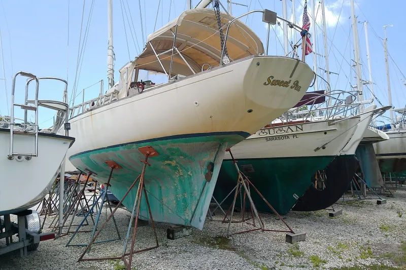 Slide: The Image of 1981 Sea Sprite 34 sailboat on stands in a boatyard, hull showing wear. - 3