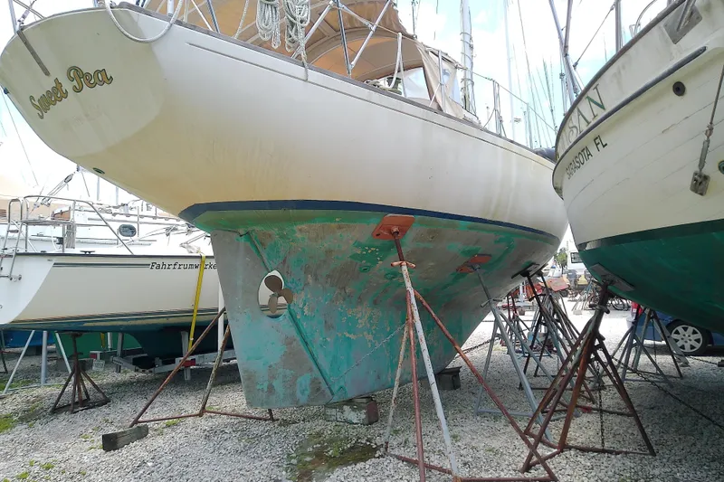 Slide: The Image of 1981 Sea Sprite 34 sailboat on stands, hull showing wear, in a boatyard setting. - 5
