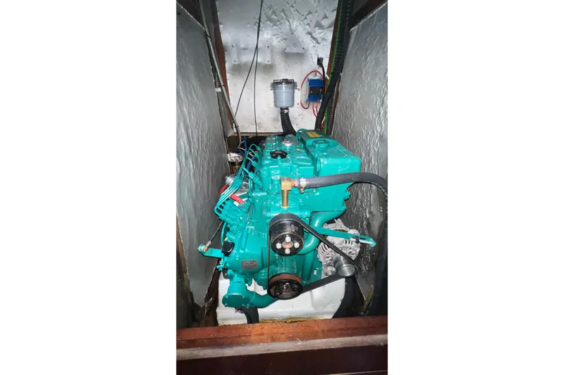 Slide: The Image of Engine compartment of a 2001 Bavaria 42 sailboat, featuring a teal marine engine. - 13