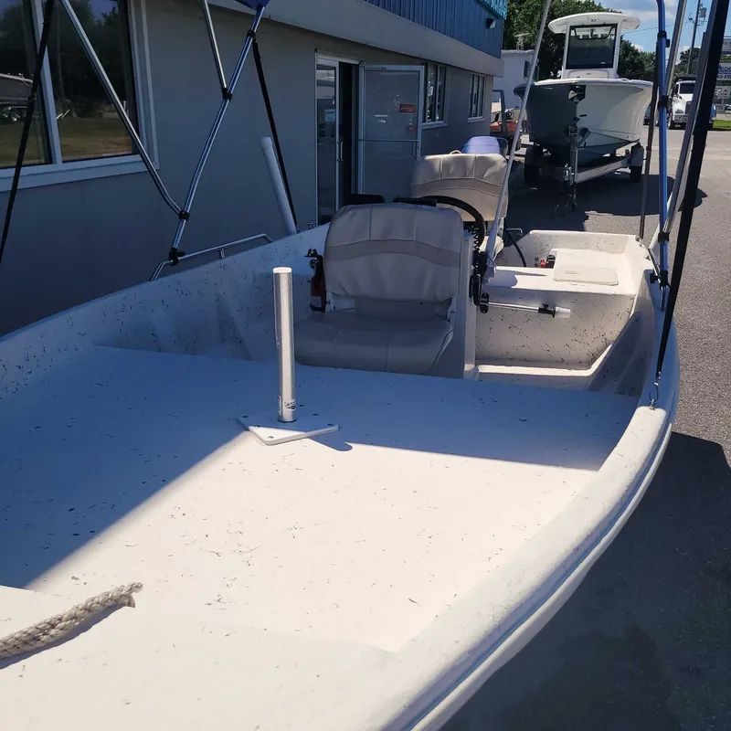 Slide: The Image of A white boat with two seats is parked next to a building. - 4