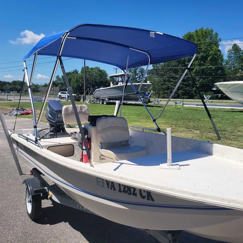 Slide: The Image of A 2002 Stinger 144CC boat with a blue bimini top on a trailer. - 7